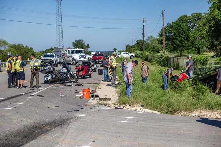 Motorcycle crash scene with emergency responders and debris on the road.